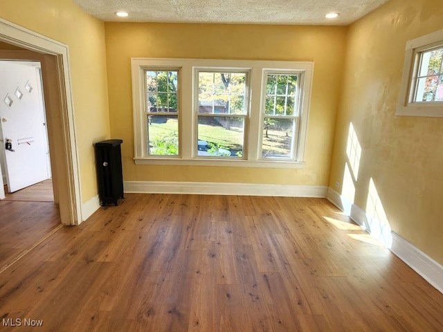 unfurnished room featuring hardwood / wood-style flooring, plenty of natural light, and a textured ceiling