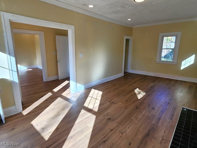 empty room featuring hardwood / wood-style floors, a textured ceiling, and crown molding