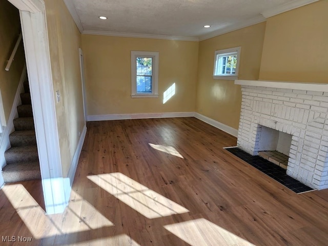 unfurnished living room with a textured ceiling, a fireplace, wood-type flooring, and crown molding