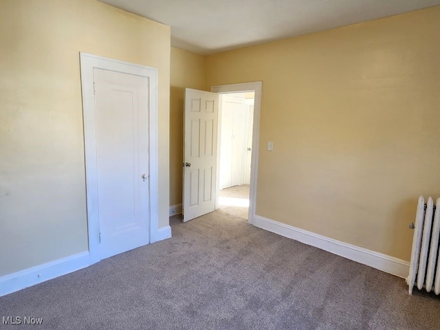 unfurnished bedroom featuring radiator and carpet flooring