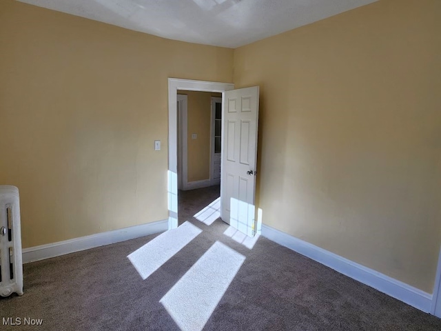 unfurnished room featuring radiator and carpet flooring