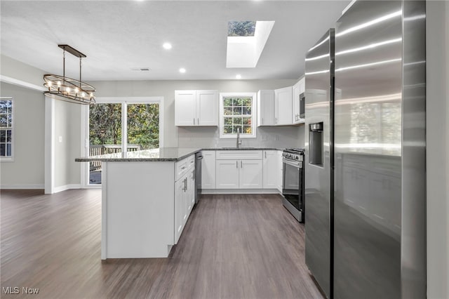 kitchen featuring appliances with stainless steel finishes, dark hardwood / wood-style floors, white cabinetry, sink, and hanging light fixtures