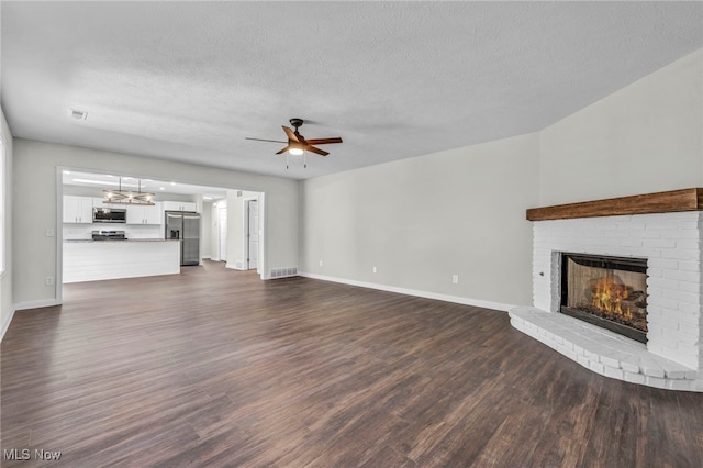 unfurnished living room featuring dark wood-type flooring, a fireplace, a textured ceiling, and ceiling fan