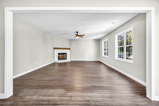 unfurnished living room featuring dark wood-type flooring, ceiling fan, and a fireplace