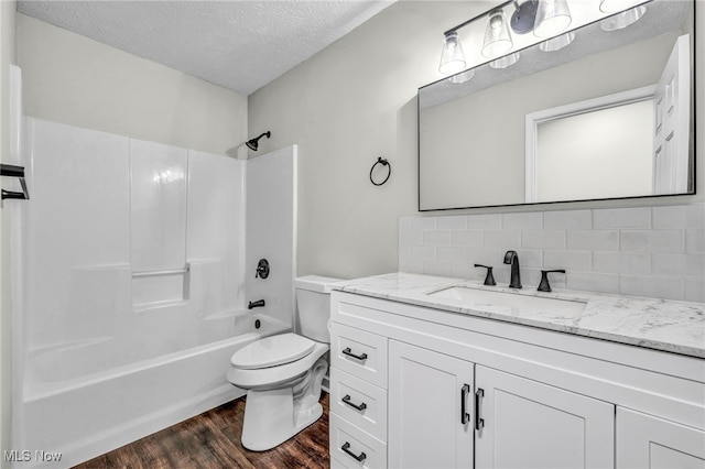 full bathroom featuring hardwood / wood-style flooring, bathing tub / shower combination, a textured ceiling, decorative backsplash, and toilet