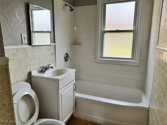 full bath featuring vanity, tile walls, toilet, and shower / washtub combination