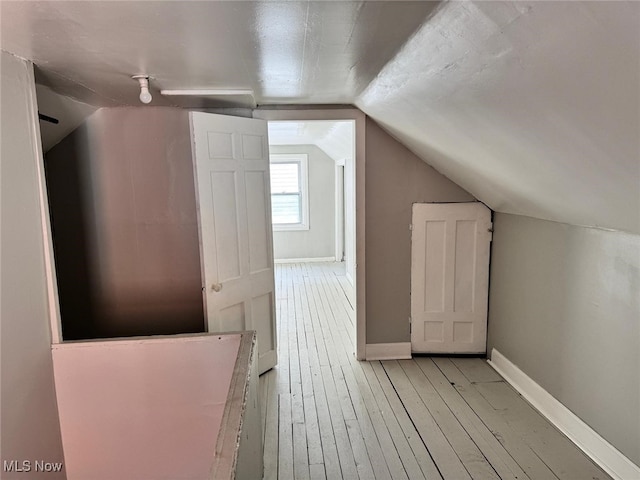 additional living space featuring lofted ceiling and light wood-type flooring