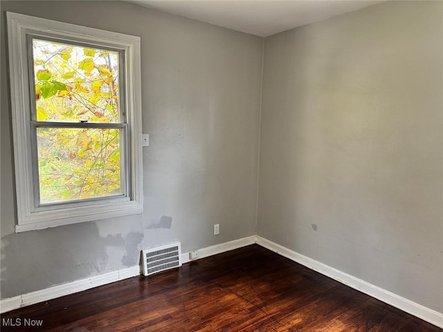 unfurnished room with plenty of natural light, wood finished floors, and visible vents