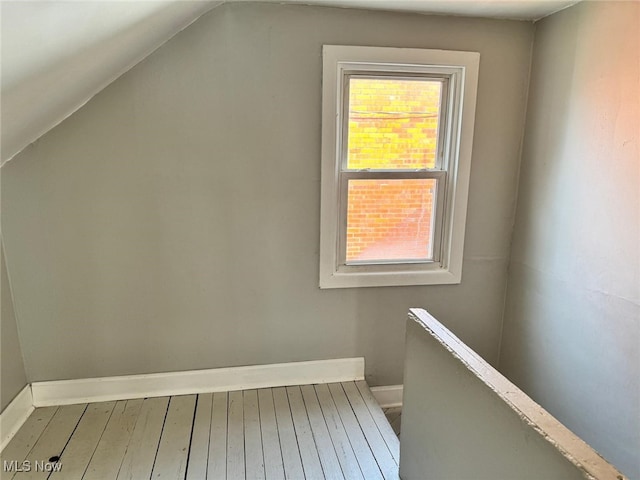 additional living space with baseboards, wood-type flooring, and lofted ceiling