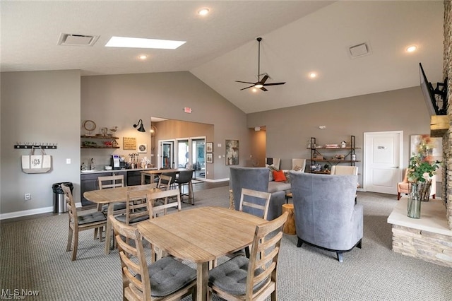 carpeted dining area with a skylight, high vaulted ceiling, and ceiling fan