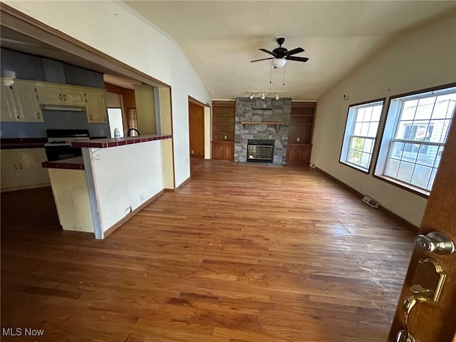 unfurnished living room with light hardwood / wood-style flooring, lofted ceiling, a fireplace, and ceiling fan