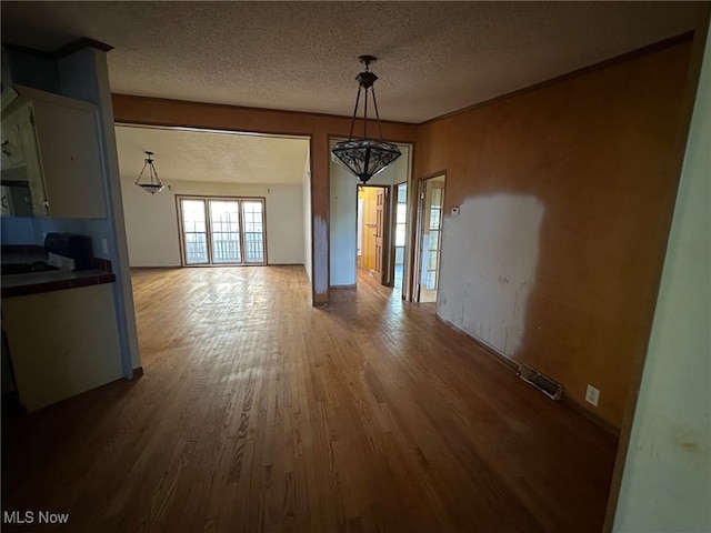 unfurnished dining area featuring wood-type flooring and a textured ceiling