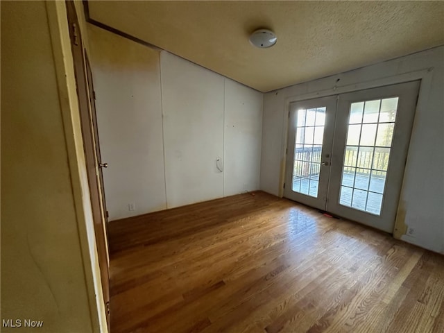 spare room featuring french doors, hardwood / wood-style flooring, and a textured ceiling