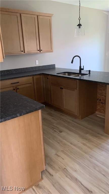 kitchen featuring sink, light hardwood / wood-style flooring, and pendant lighting