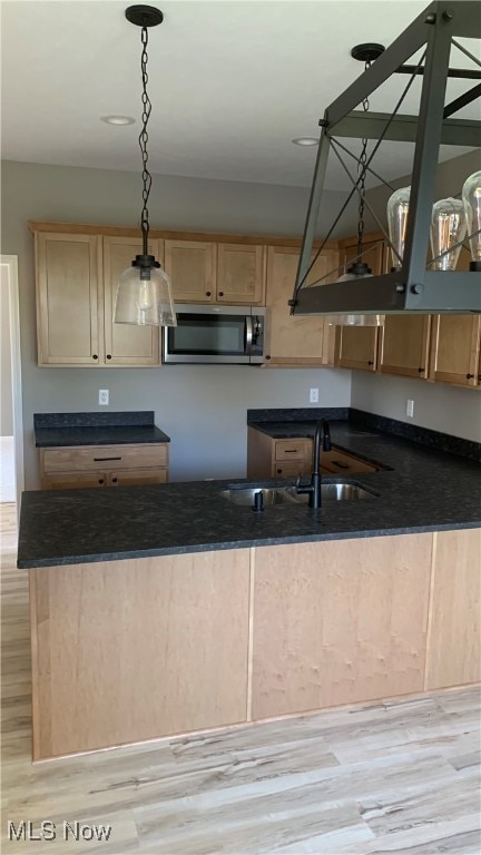 kitchen with light brown cabinetry, sink, decorative light fixtures, and light wood-type flooring