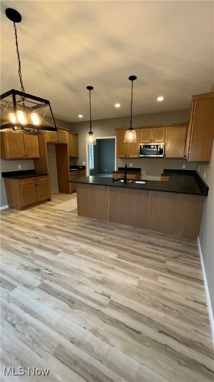 kitchen featuring light hardwood / wood-style floors, kitchen peninsula, sink, and hanging light fixtures