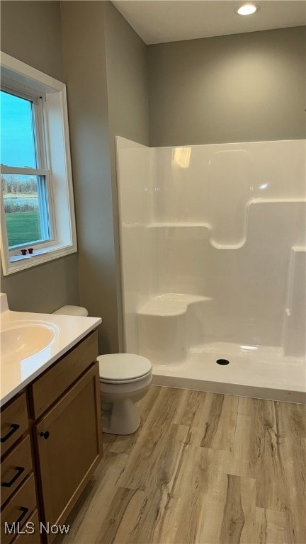 bathroom with toilet, hardwood / wood-style floors, vanity, and a shower