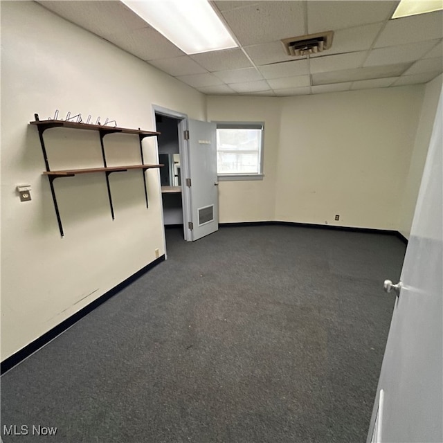 spare room featuring a drop ceiling and dark carpet