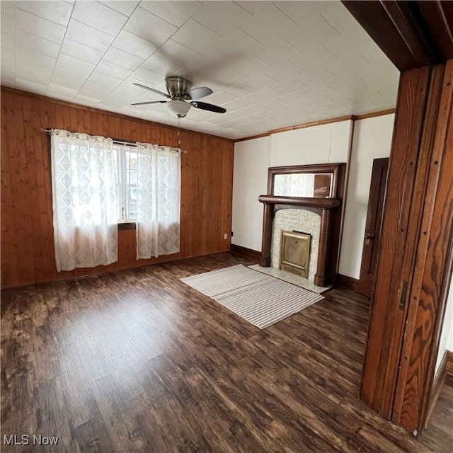 unfurnished living room with dark hardwood / wood-style floors, wooden walls, and ceiling fan