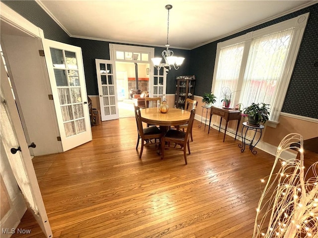 dining room with hardwood / wood-style floors, crown molding, french doors, and a notable chandelier