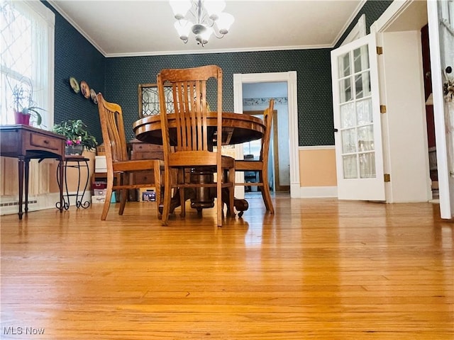 dining area with light wood-type flooring, an inviting chandelier, ornamental molding, and a baseboard heating unit