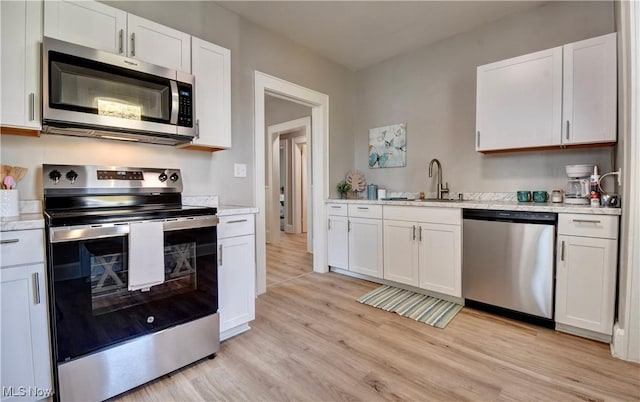 3219 11th St SW, Canton, OH 44710 - kitchen featuring white cabinetry, appliances with stainless steel finishes, a sink, and light wood finished floors