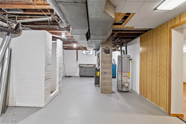 basement with water heater, heating unit, and wood walls