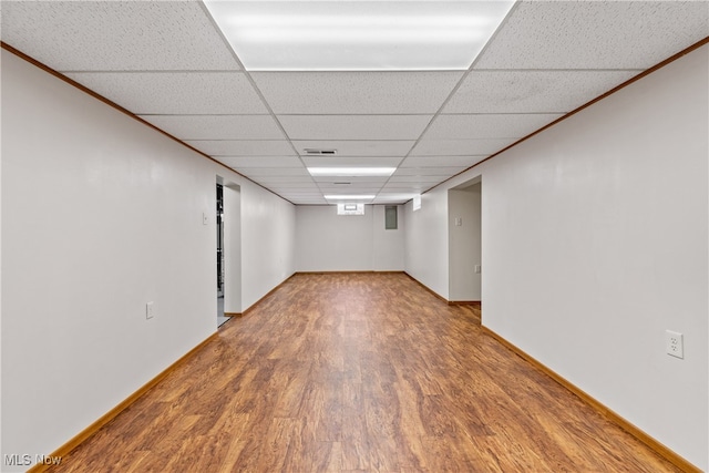 basement with a drop ceiling, crown molding, and hardwood / wood-style flooring