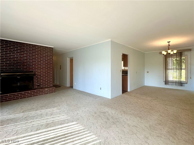 unfurnished living room with an inviting chandelier, carpet flooring, a fireplace, and crown molding