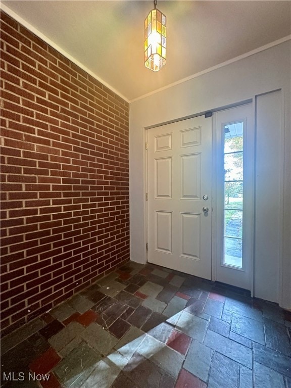 entryway with brick wall and crown molding