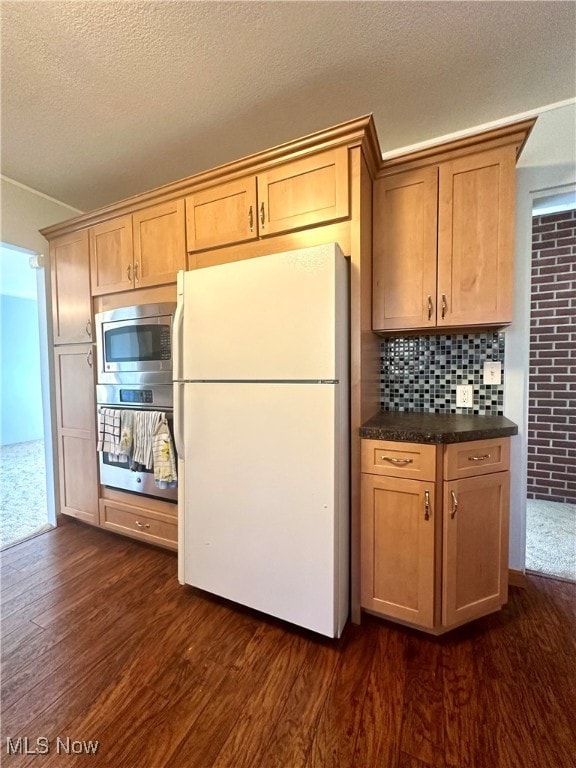 kitchen with dark wood-type flooring, stainless steel appliances, decorative backsplash, and a textured ceiling