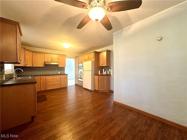 kitchen with sink, ceiling fan, decorative backsplash, white refrigerator, and dark hardwood / wood-style floors