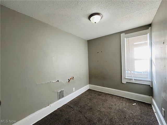 empty room featuring a textured ceiling and dark colored carpet