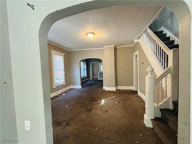 carpeted entryway featuring crown molding and a textured ceiling