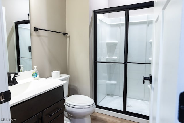 bathroom featuring a shower with door, vanity, hardwood / wood-style floors, and toilet