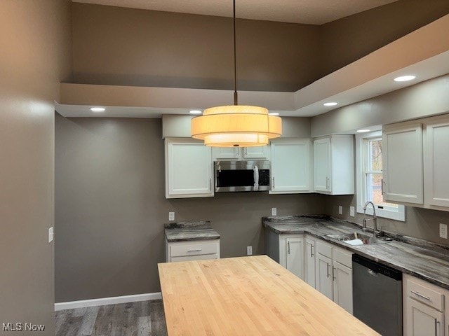 kitchen featuring sink, appliances with stainless steel finishes, decorative light fixtures, and white cabinets