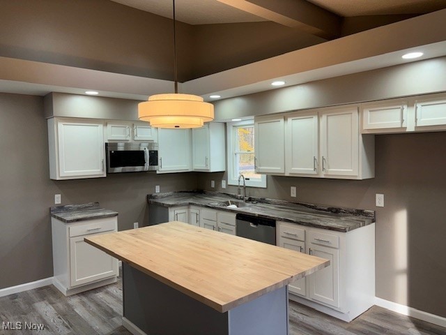 kitchen with a kitchen island, hardwood / wood-style floors, stainless steel appliances, pendant lighting, and white cabinets