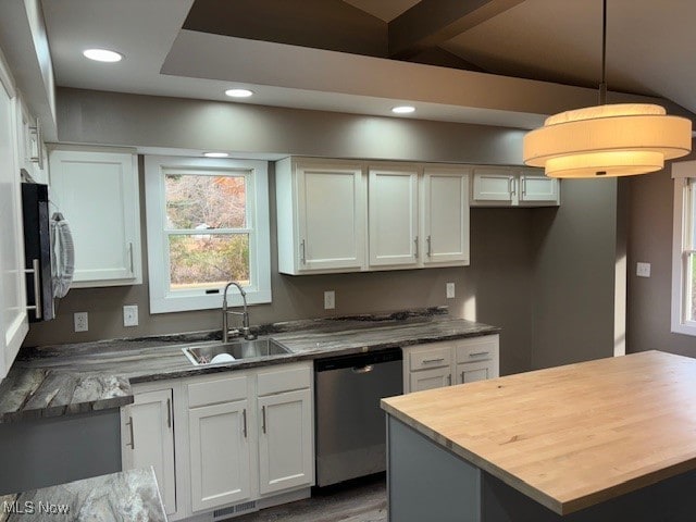 kitchen with appliances with stainless steel finishes, sink, white cabinetry, dark stone counters, and pendant lighting