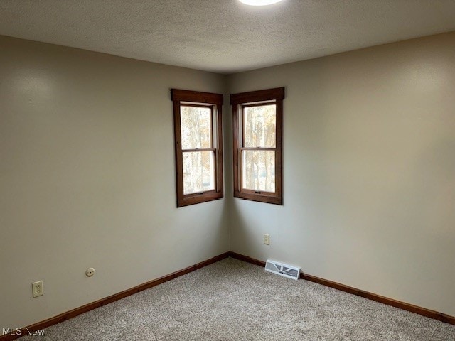 carpeted spare room with a textured ceiling