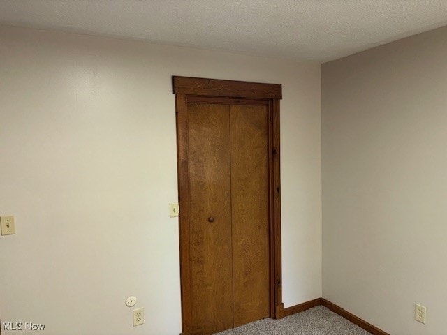 unfurnished bedroom featuring a textured ceiling and light colored carpet