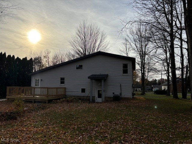 back house at dusk with a yard and a wooden deck