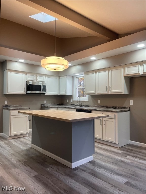 kitchen with white cabinets, decorative light fixtures, and light wood-type flooring