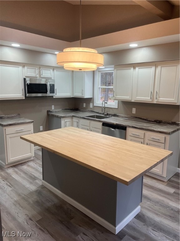 kitchen featuring appliances with stainless steel finishes, white cabinetry, decorative light fixtures, and sink