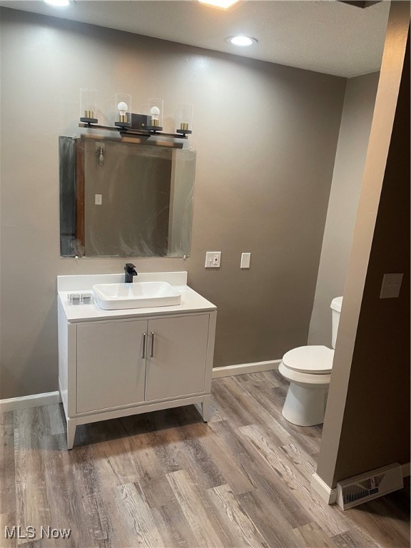 bathroom featuring vanity, wood-type flooring, and toilet