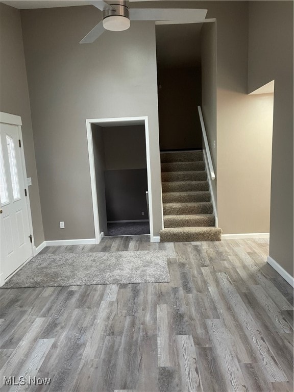 entrance foyer with a towering ceiling, wood-type flooring, and ceiling fan