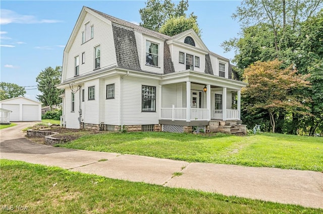 view of front facade with covered porch, an outbuilding, and a front lawn