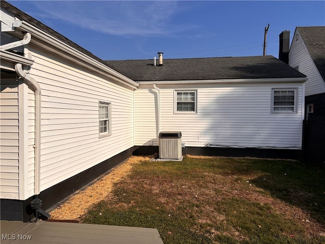 view of side of property featuring central AC and a lawn