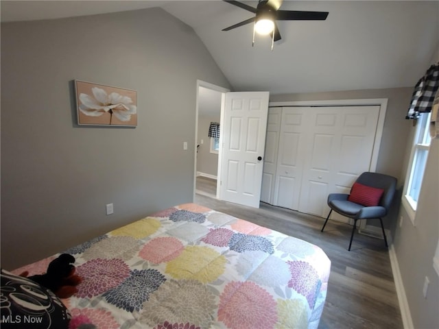 bedroom with dark hardwood / wood-style floors, vaulted ceiling, a closet, and ceiling fan