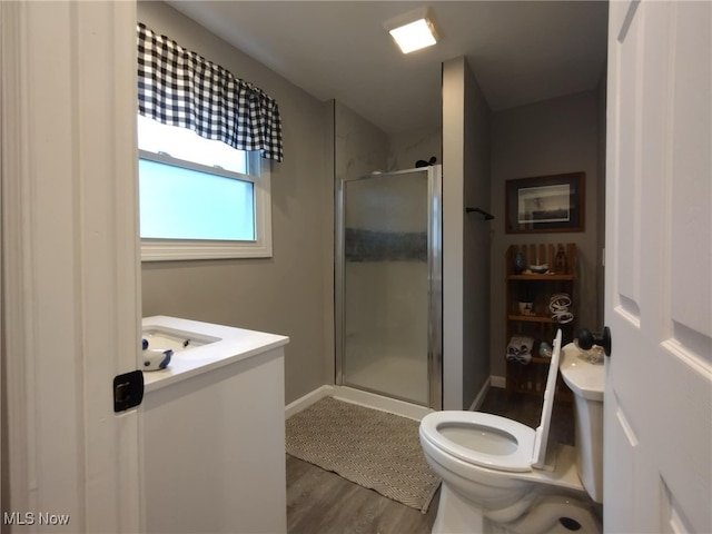 bathroom featuring wood-type flooring, vanity, toilet, and a shower with door