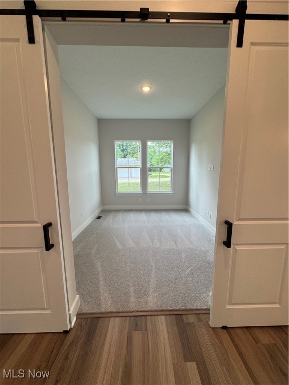 unfurnished room featuring a barn door and hardwood / wood-style flooring